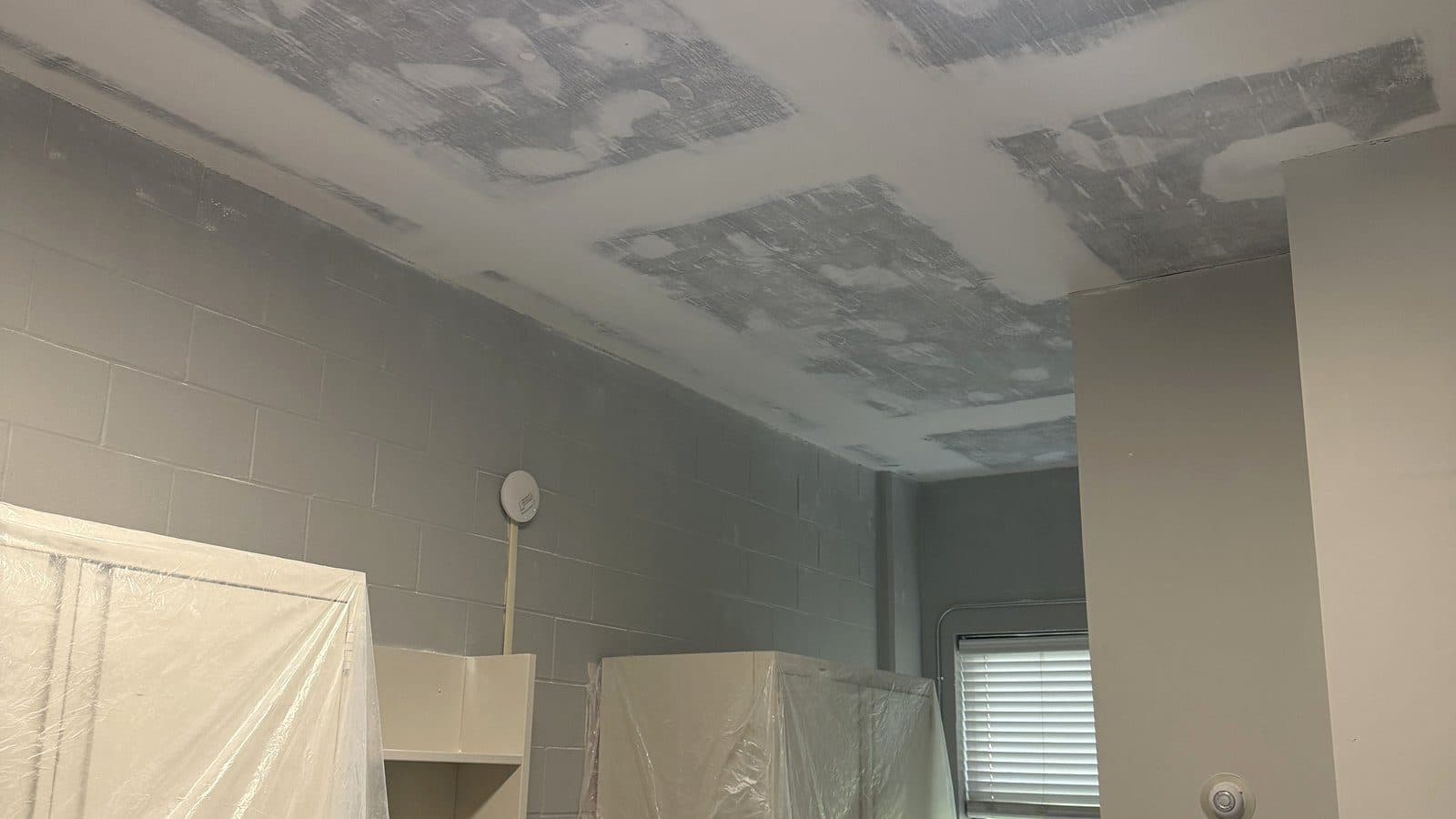 Ceiling repair in an occupied building in Huntsville, AL, with furniture wrapped and protected while work continues